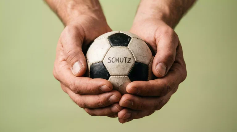 Verantwortungsvolles Wetten – Schützende Hand über einem kleinen Fußball symbolisiert Spielerschutz
